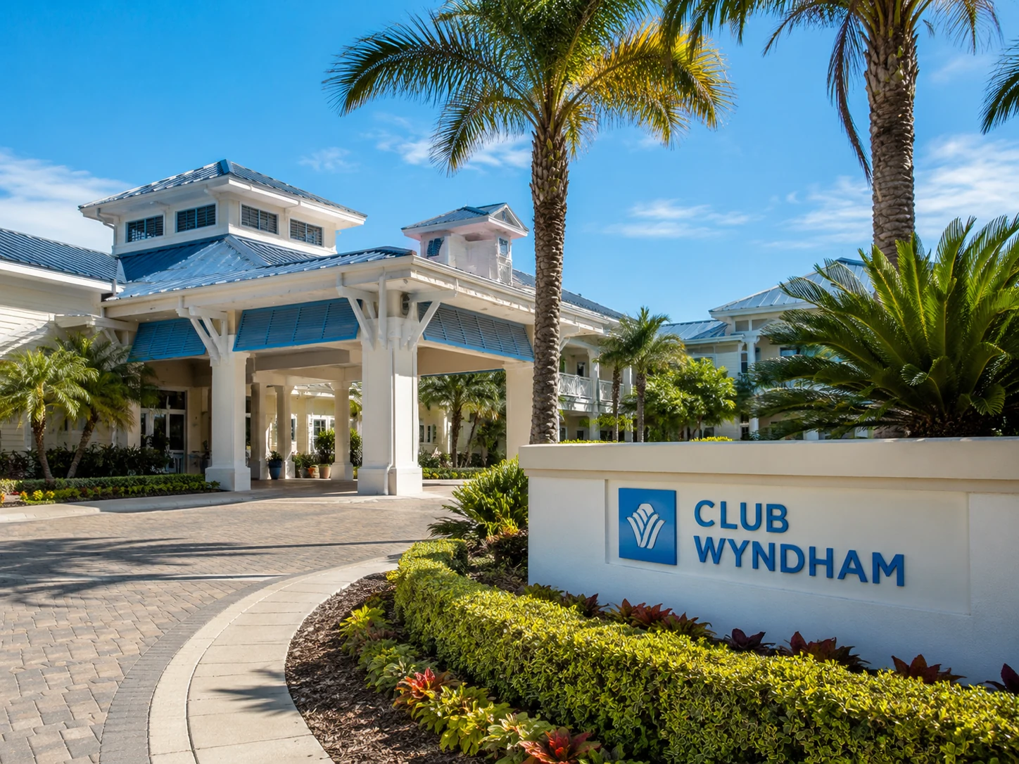 Club Wyndham-style resort entrance with palm trees, landscaping, and a resort building representing vacation ownership and resort access.